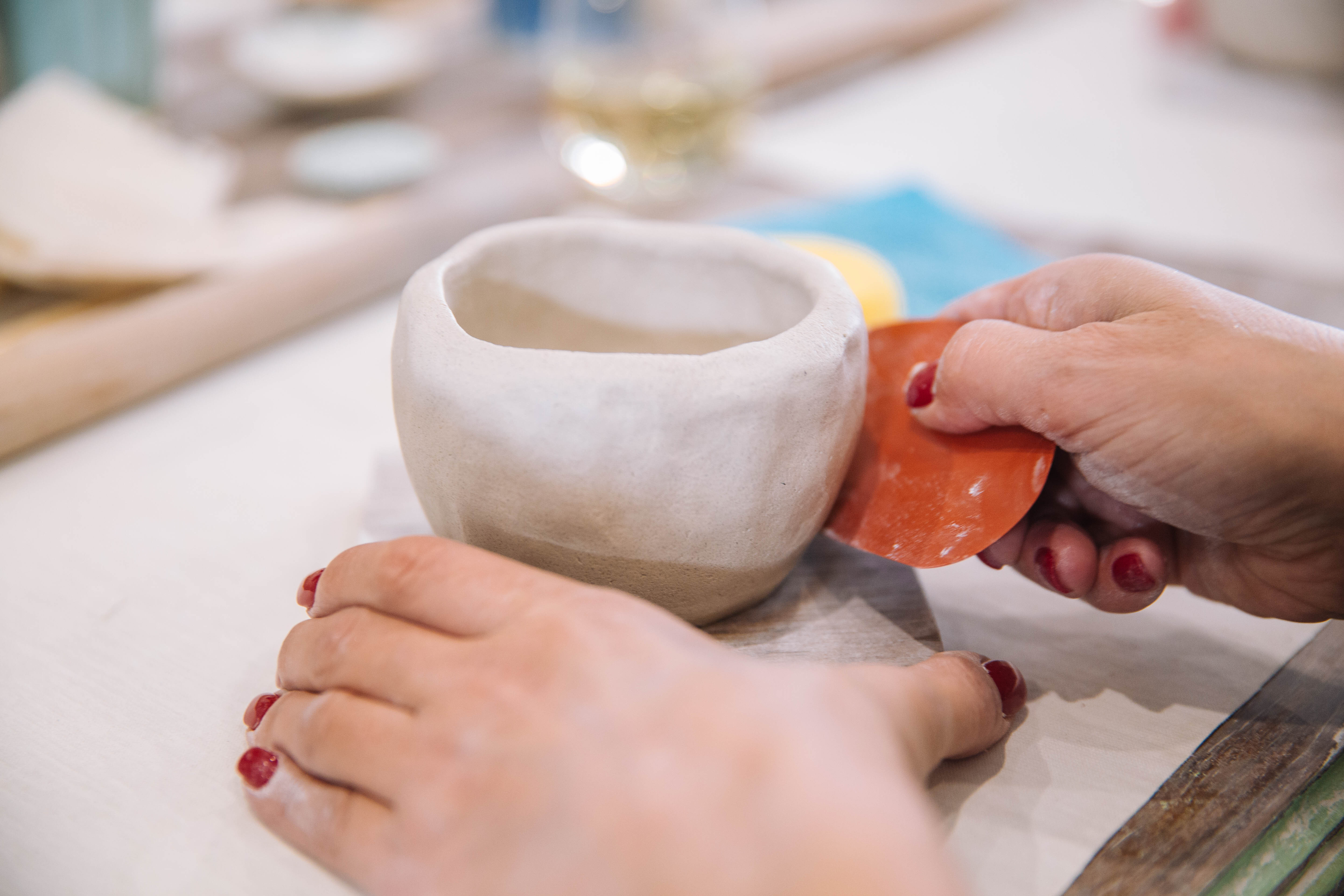 Person using a small tool to shape a clay vessel